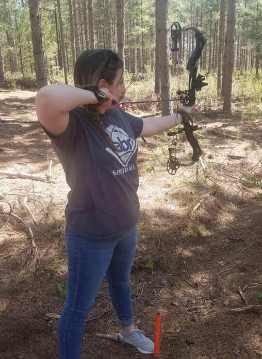 A woman aims a bow and arrow