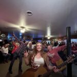 Singer SJ McDonald stands with her guitar in front of a crowd.