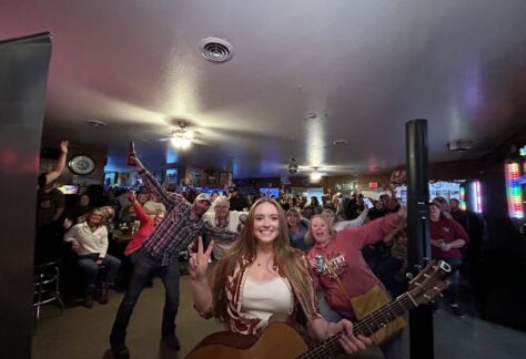Singer SJ McDonald stands with her guitar in front of a crowd.