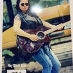 Musician Brooke Nunn poses in sunglasses with her guitar.