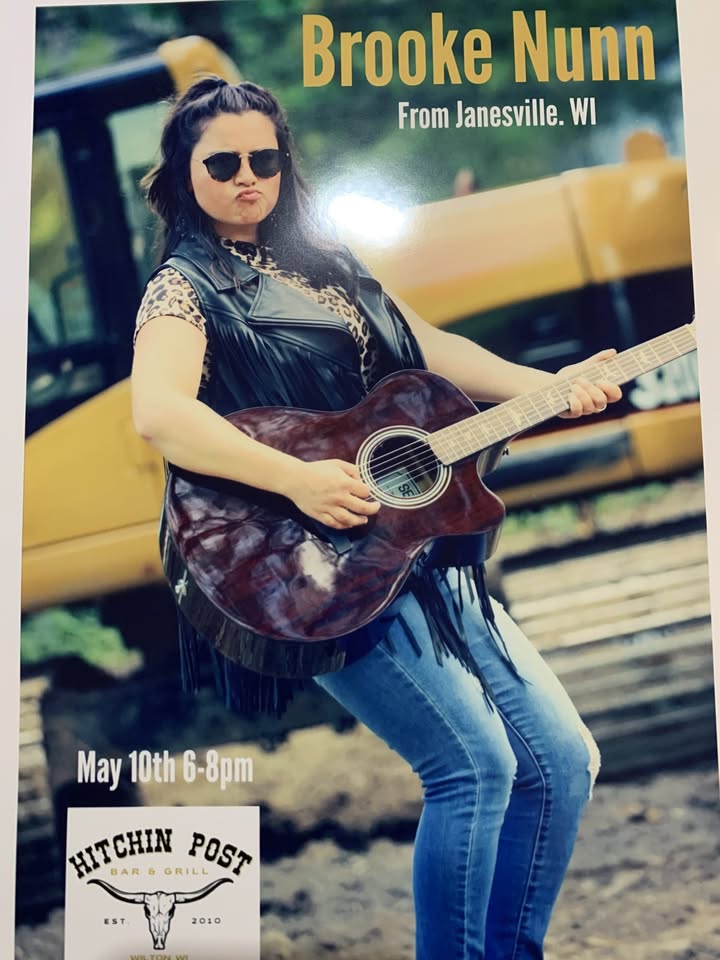 Musician Brooke Nunn poses in sunglasses with her guitar.