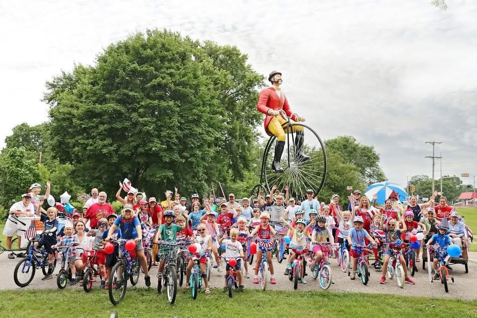 A large group of bicyclists wearing red white and blue.