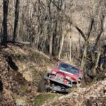 A jeep driving through a gully in the woods