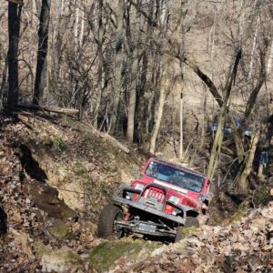 A jeep driving through a gully in the woods