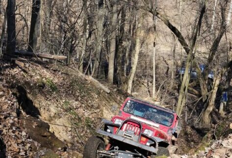 A jeep driving through a gully in the woods