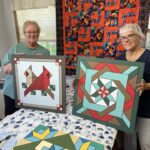 two women display their painted barn quilt boards