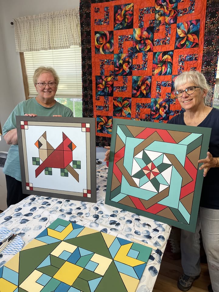 Two women holding up their barn quilts