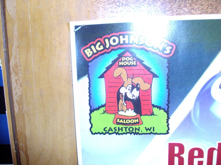 A poster with a picture of a dog in a doghouse sitting behind a bowl of dog food.