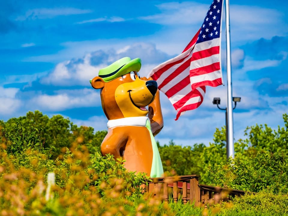 A statue of Yogi Bear saluting beside a waving American flag