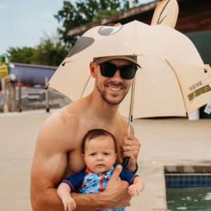 A picture of a man with a beard smiles while holding a baby