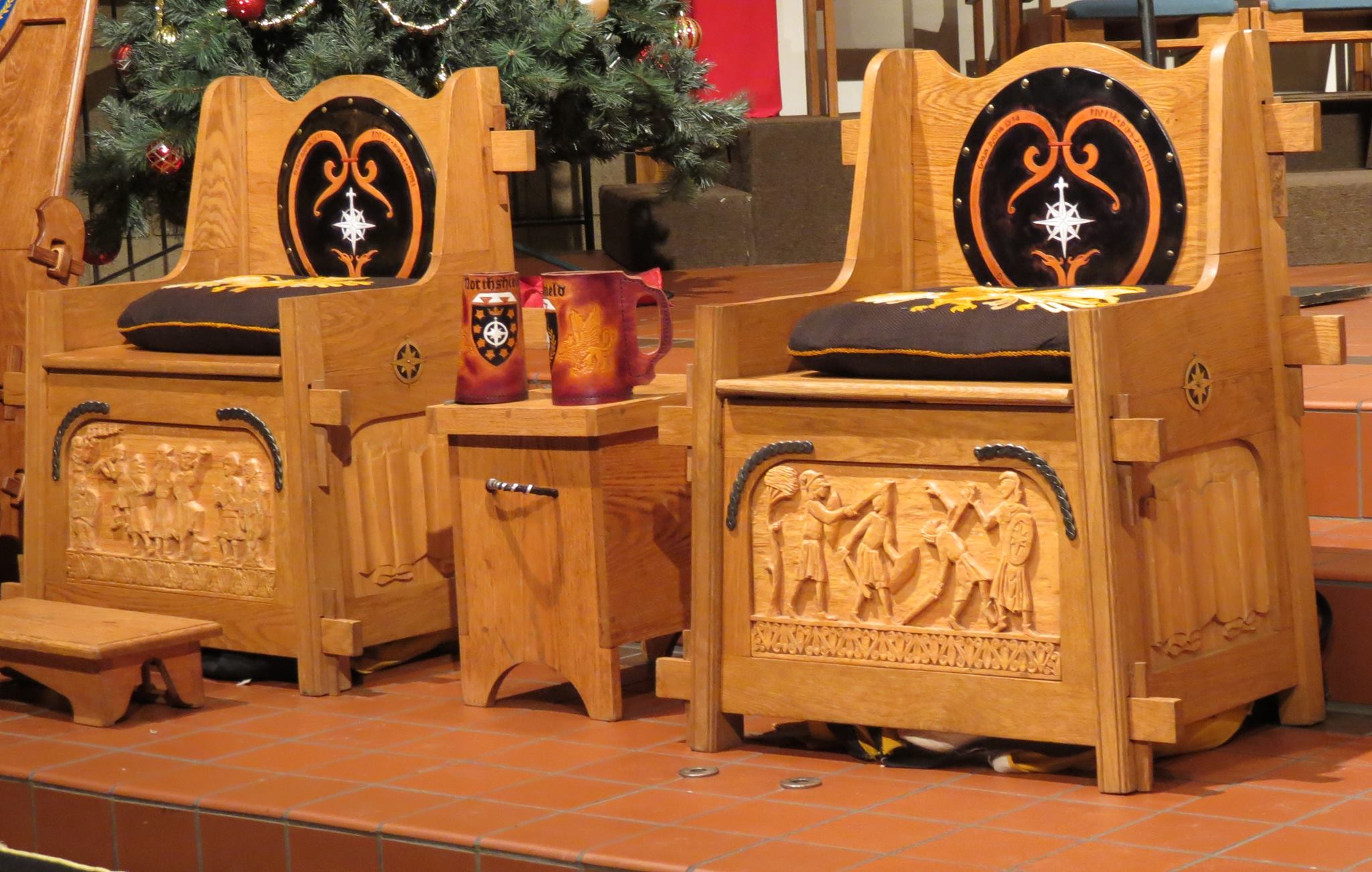 Two ornate wooden thrones with high backs, featuring black velvet cushions embroidered with golden designs