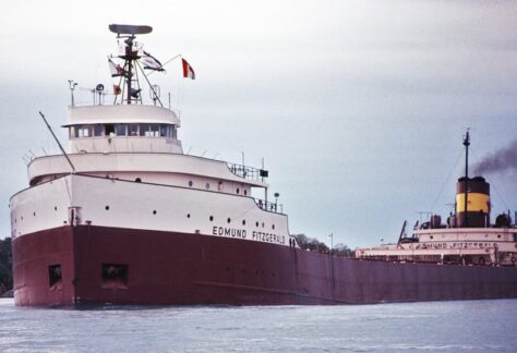 A picture of a ship in front of another boat on open water.
