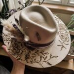 A cowboy hat with a floral design burned into it.