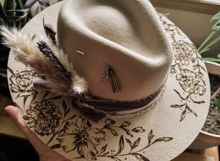 A cowboy hat with a floral design burned into it.
