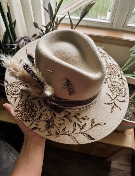 A cowboy hat with a floral design burned into it.