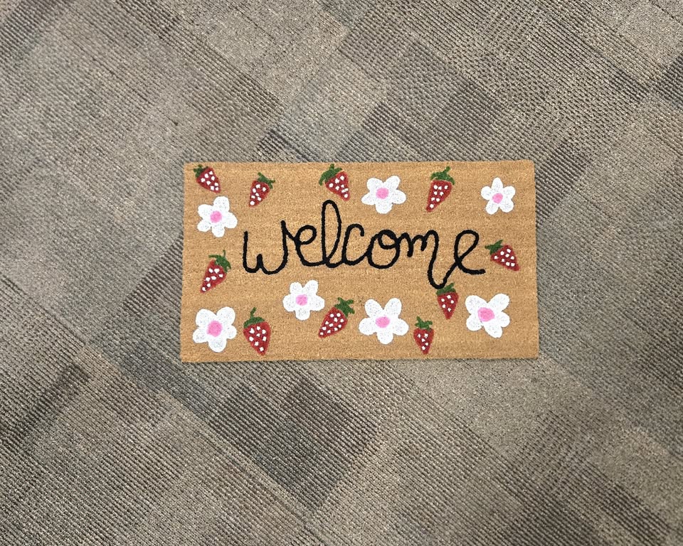 a welcome doormat with strawberries and flowers