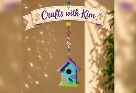 A small painted bird house hanging from a string of beads