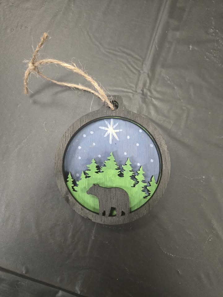 A woodcut ornament of a bear in the woods.