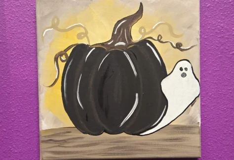 A ghost peeking out from behind a pumpkin